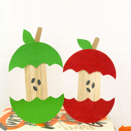 two apple cores made out of paper and popsicle sticks