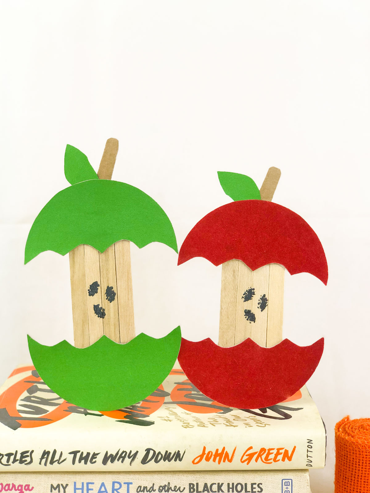 two apple cores made out of paper and popsicle sticks
