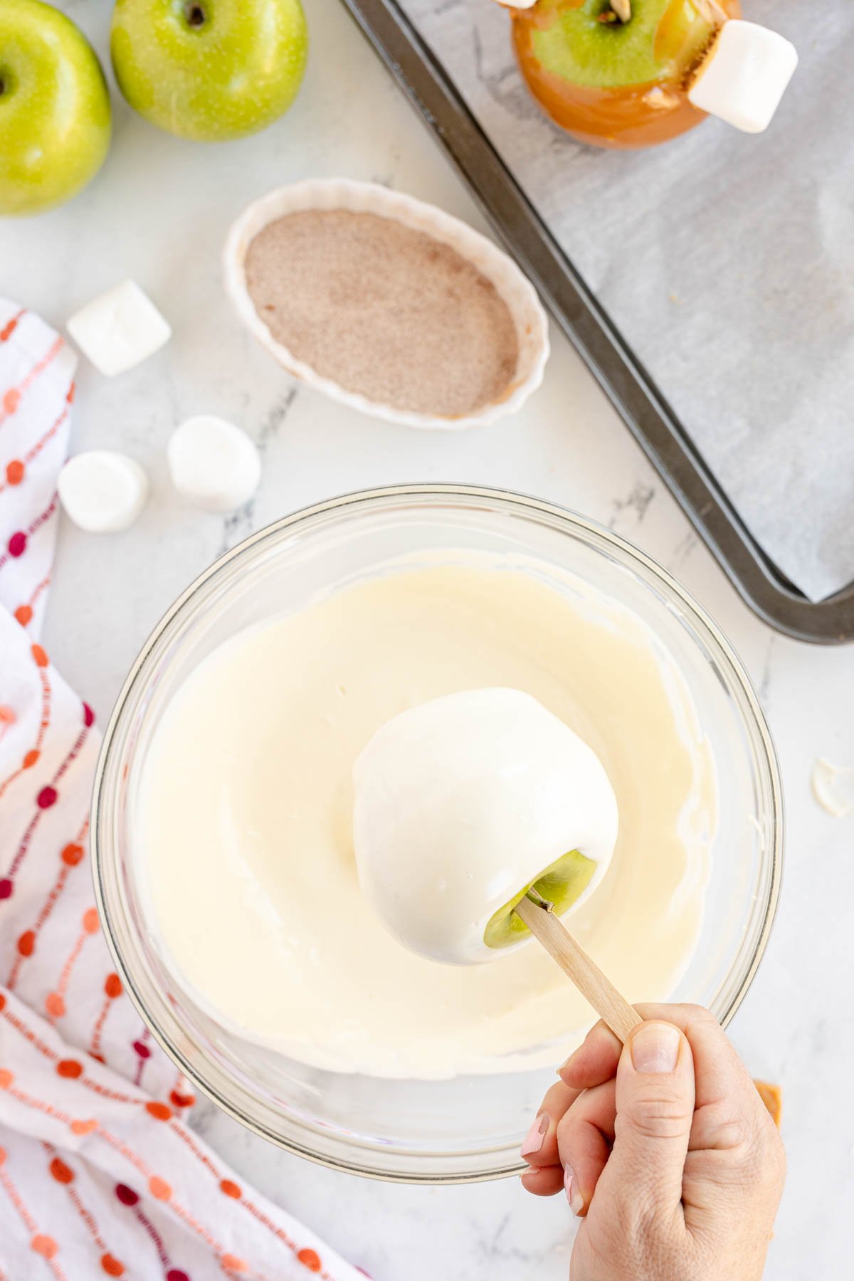 dipping a caramel apple in white chocolate