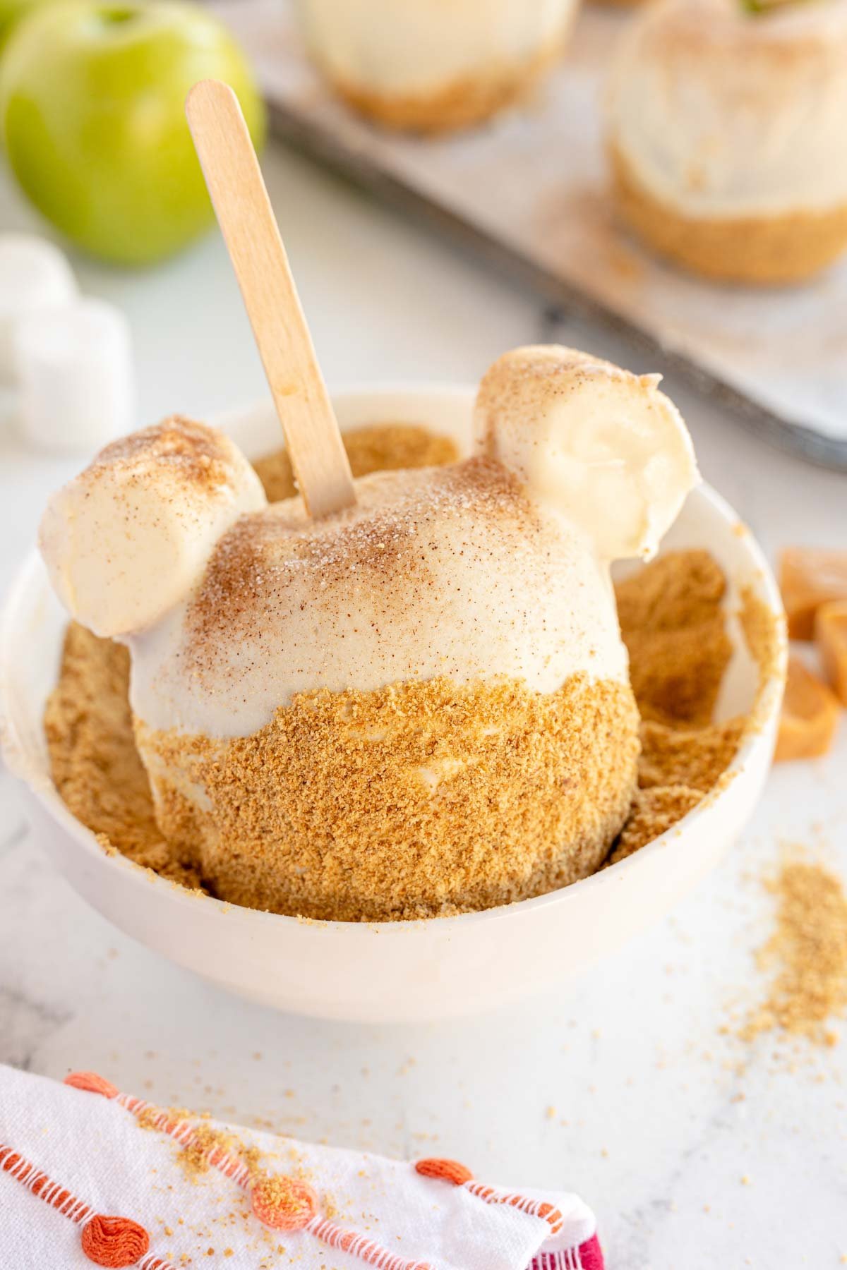 apple pie caramel apple being dipped in graham cracker crumbs