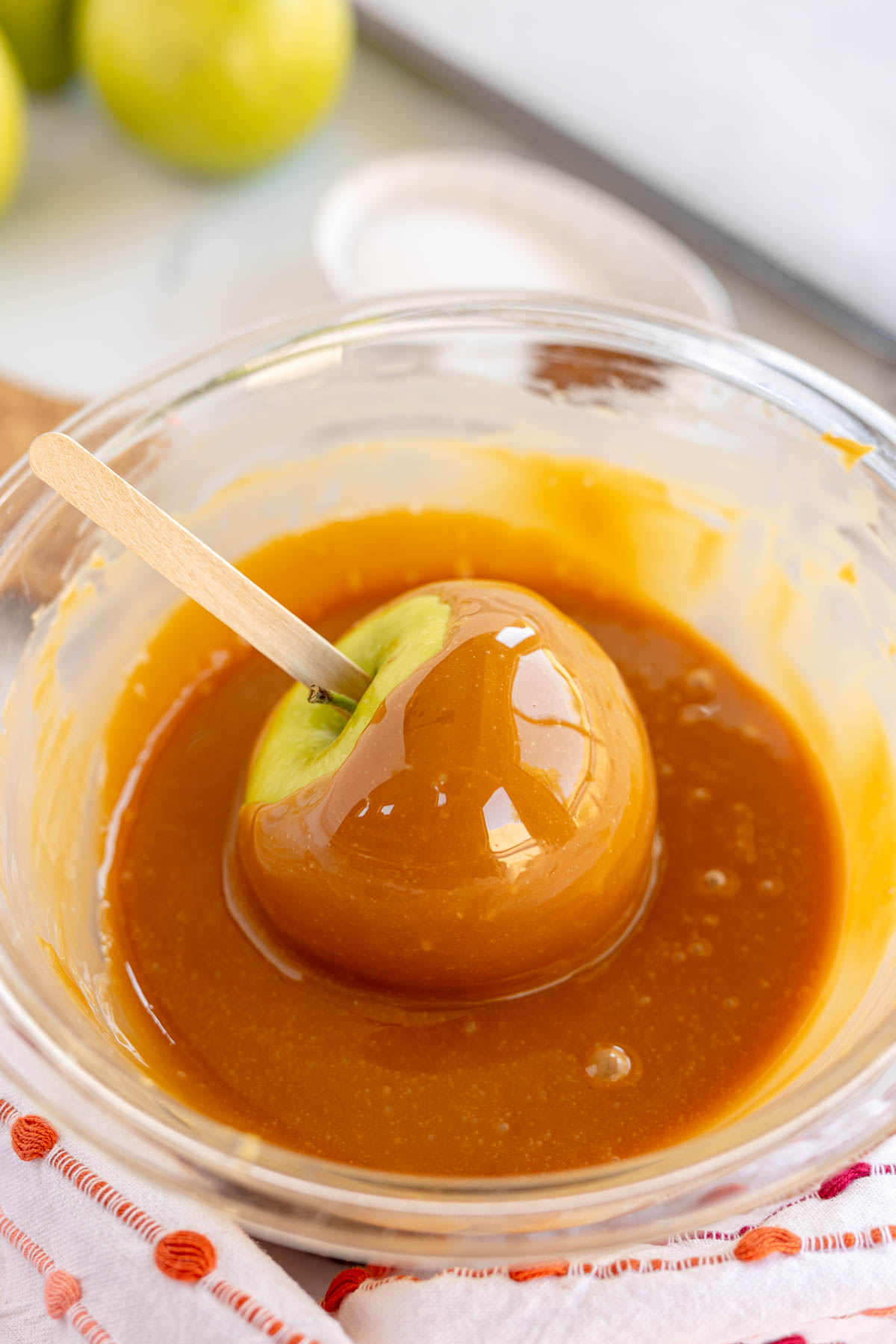dipping a green apple into a bowl of caramel