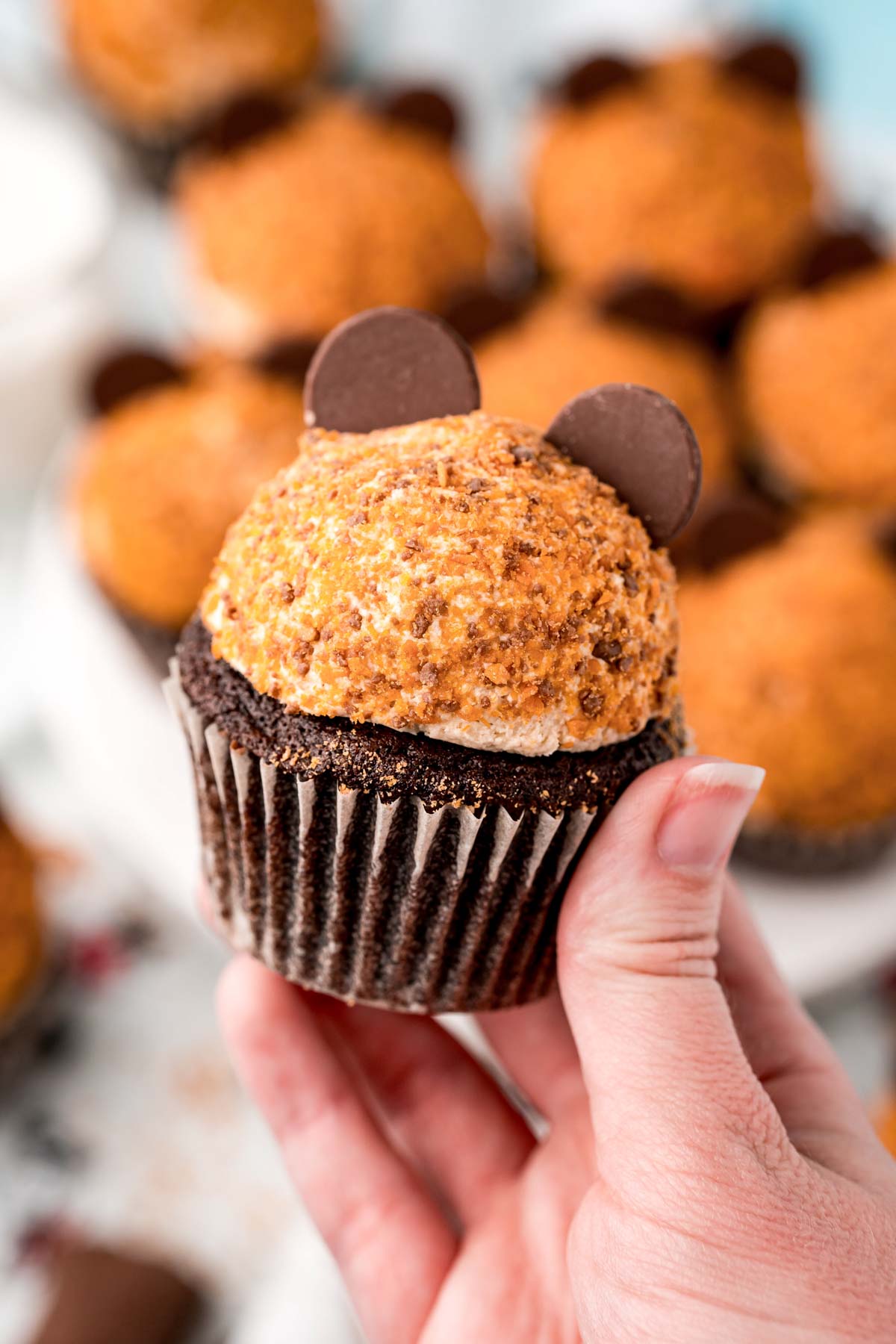 hand holding a butterfinger cupcake with Mickey ears