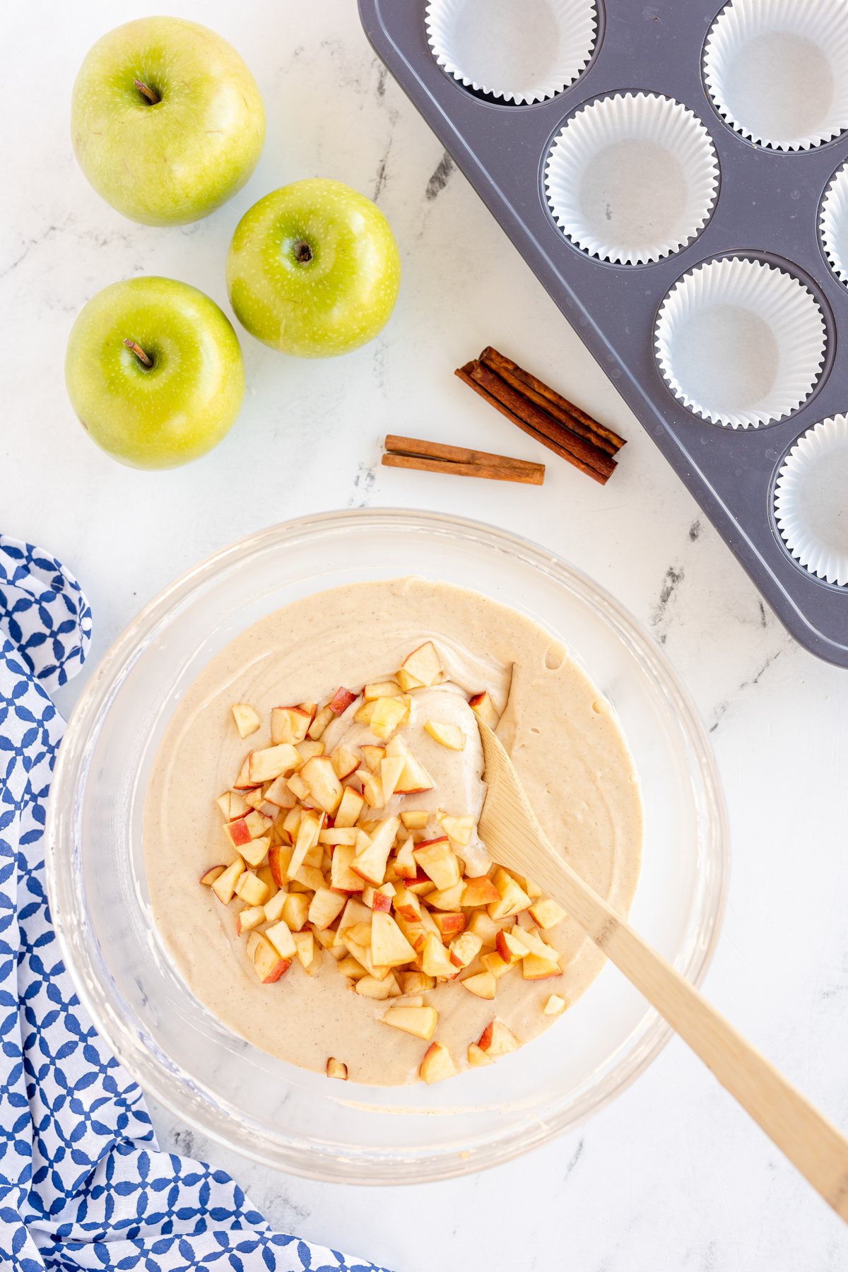 glass bowl with chopped apples and cupcake batter