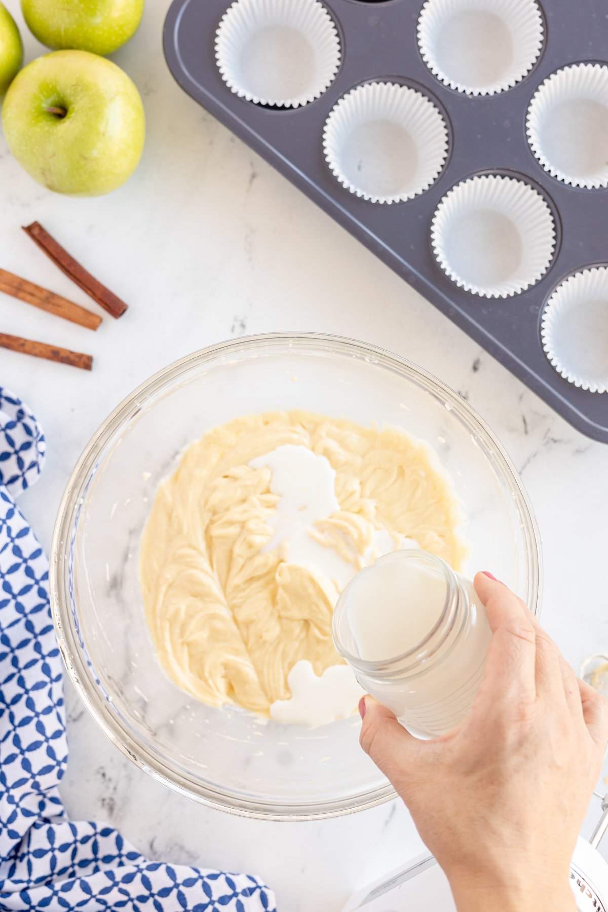 woman pouring milk into a bowl with dry ingredients