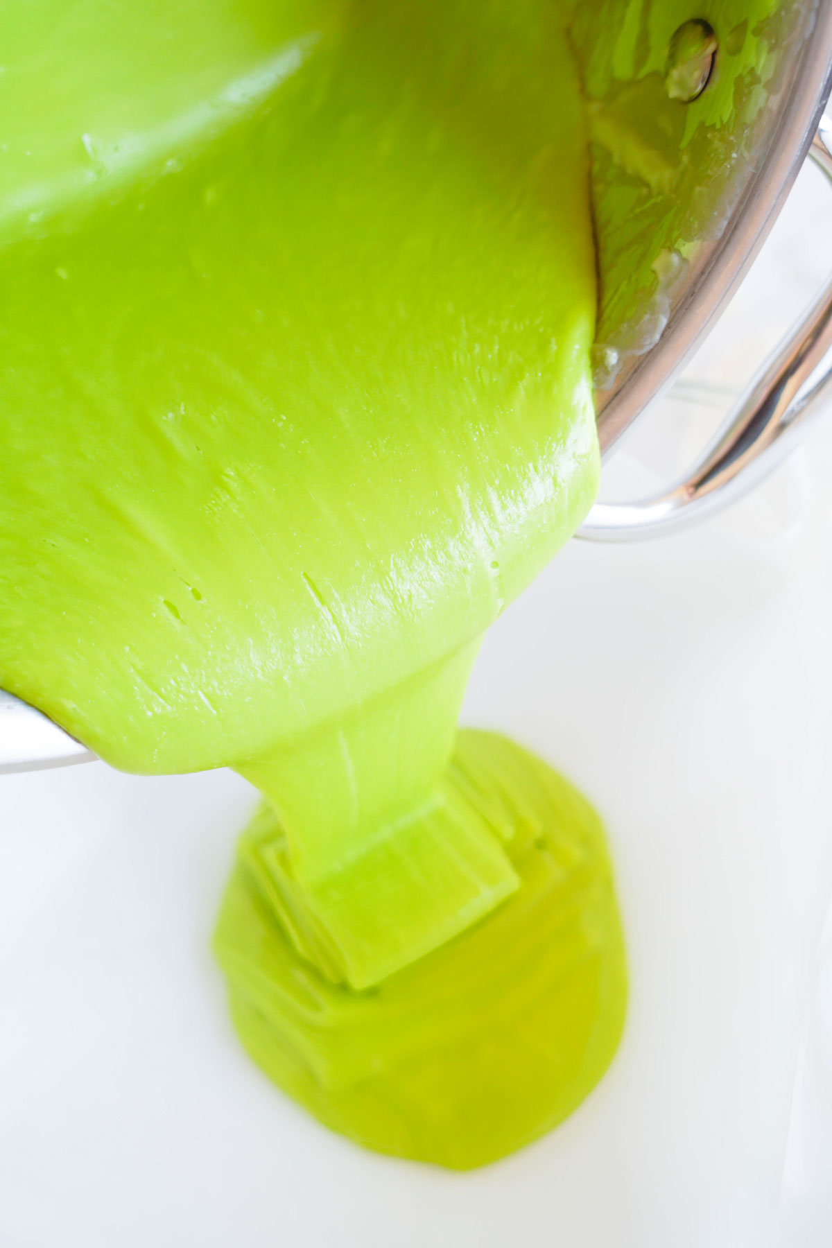 pouring green Grinch fudge mixture into a baking dish