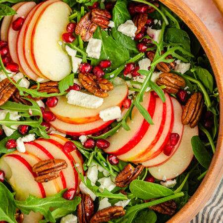 pomegranate feta salad with apple slices in a wood bowl