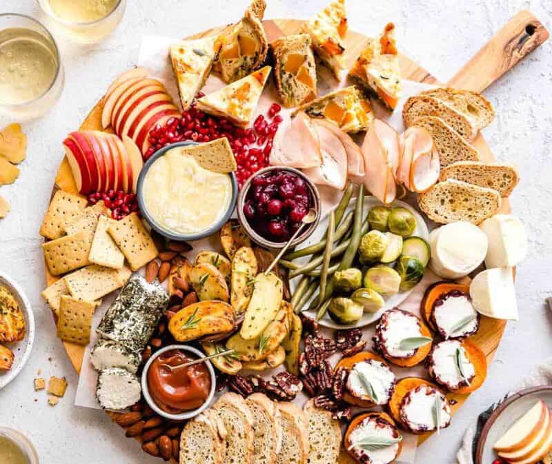 variety of vegetables, cheese, and crackers on a round board