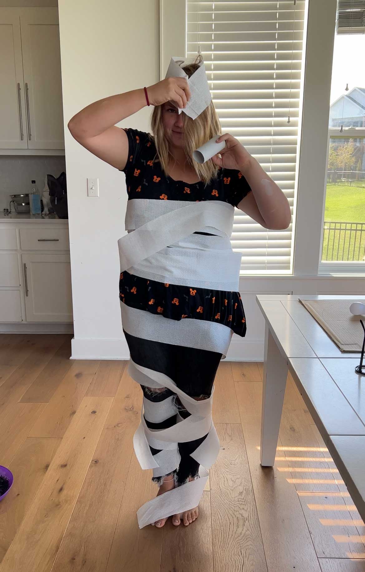 woman wrapping herself like a mummy in toilet paper