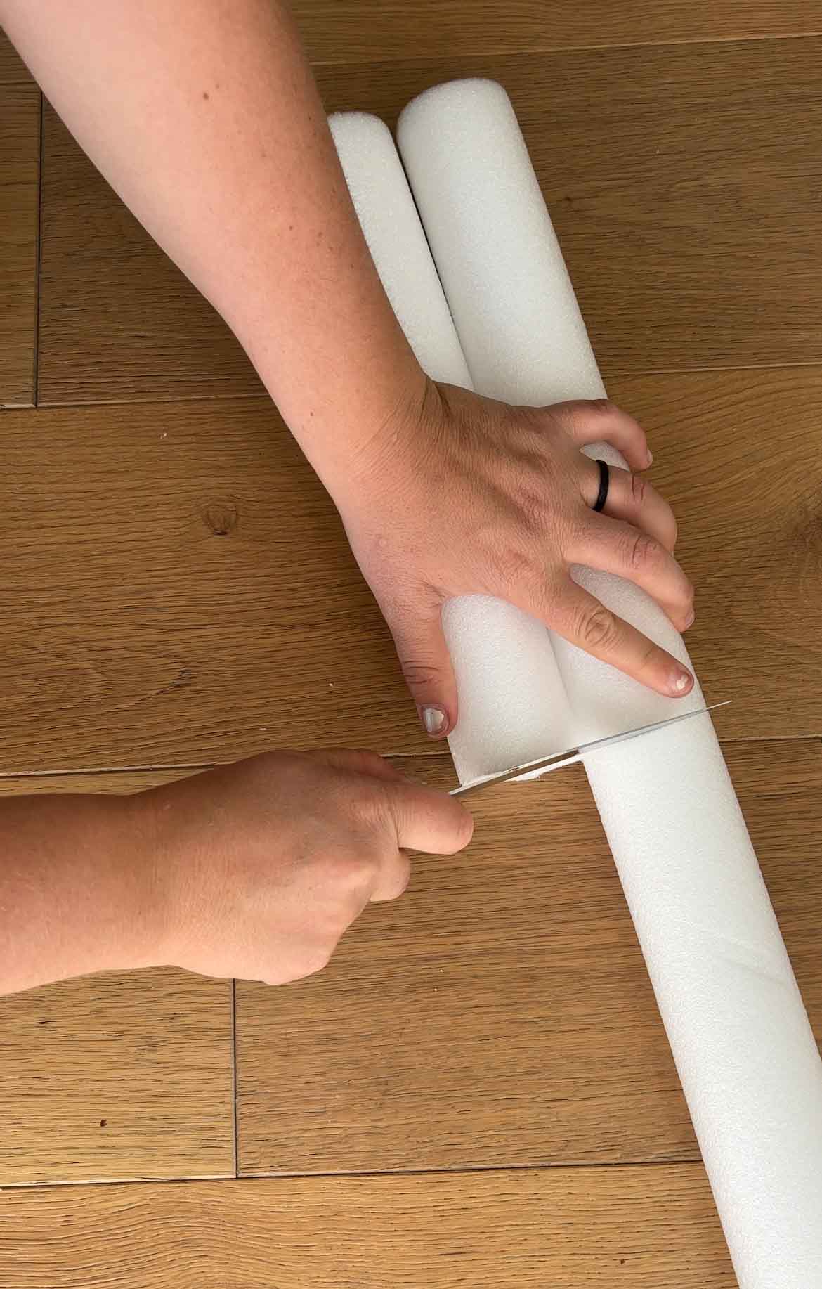 hand cutting white pool noodles