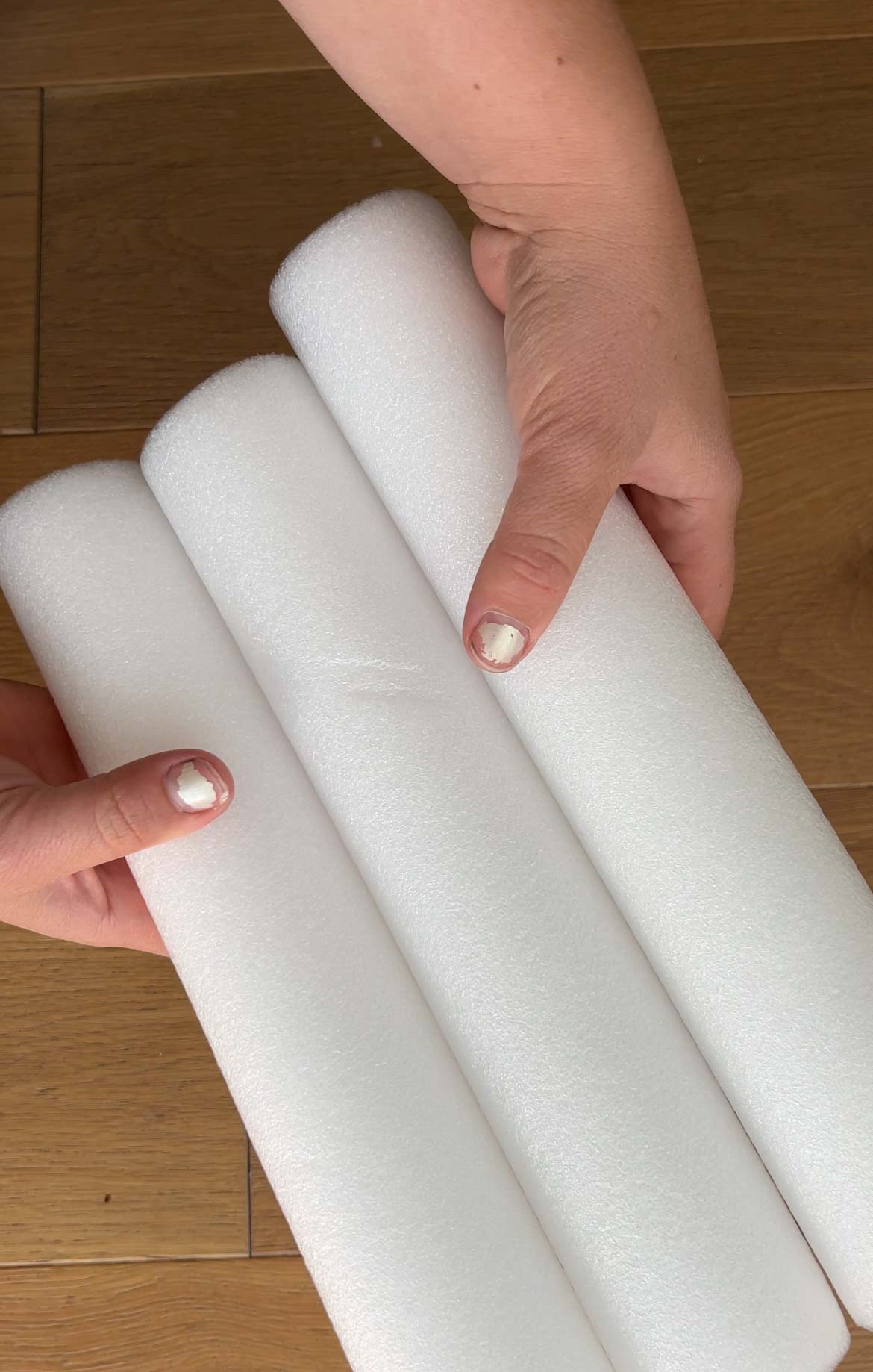 hand holding three pieces of white pool noodles