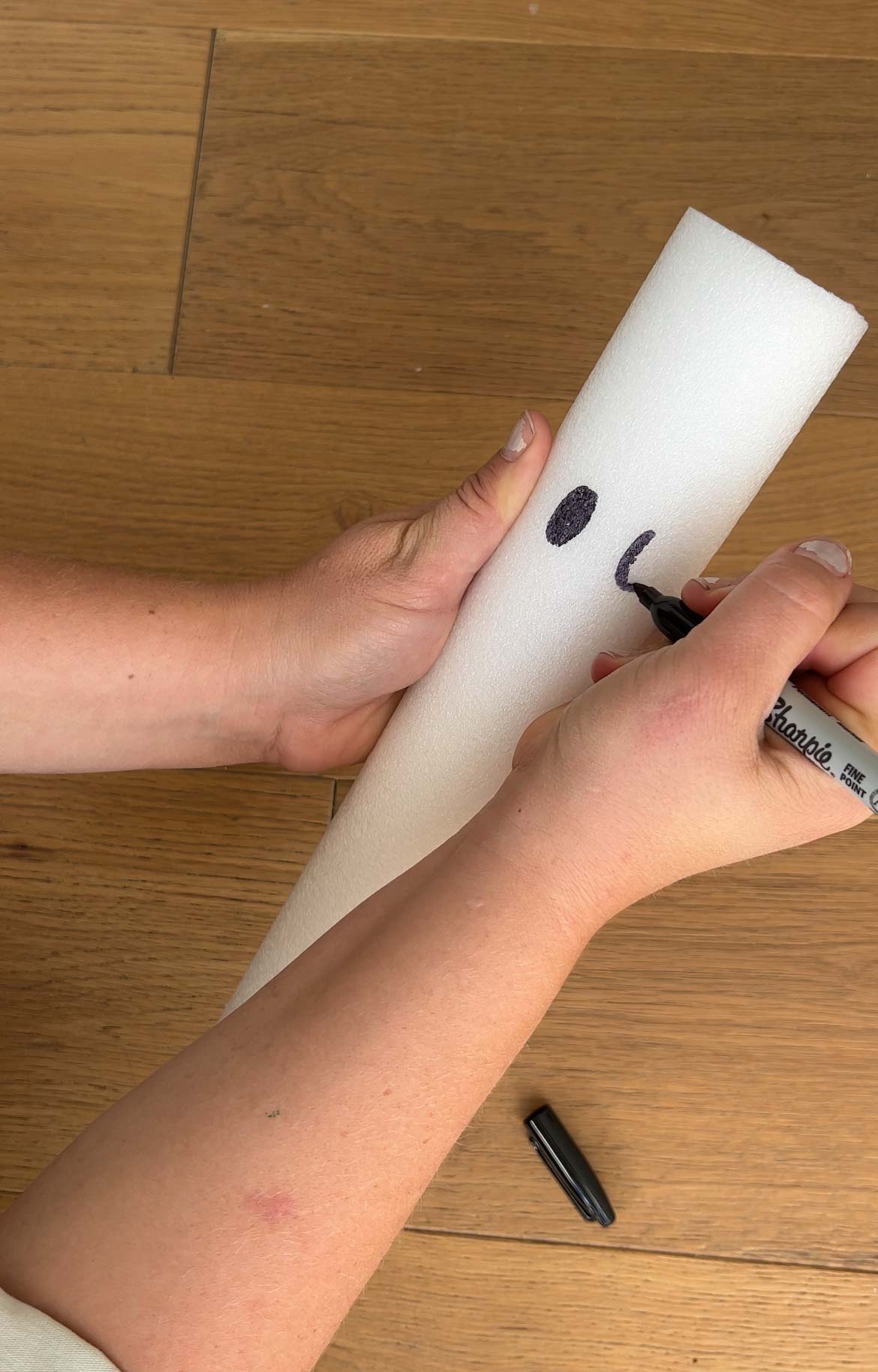 hand writing on a piece of white pool noodle with black marker