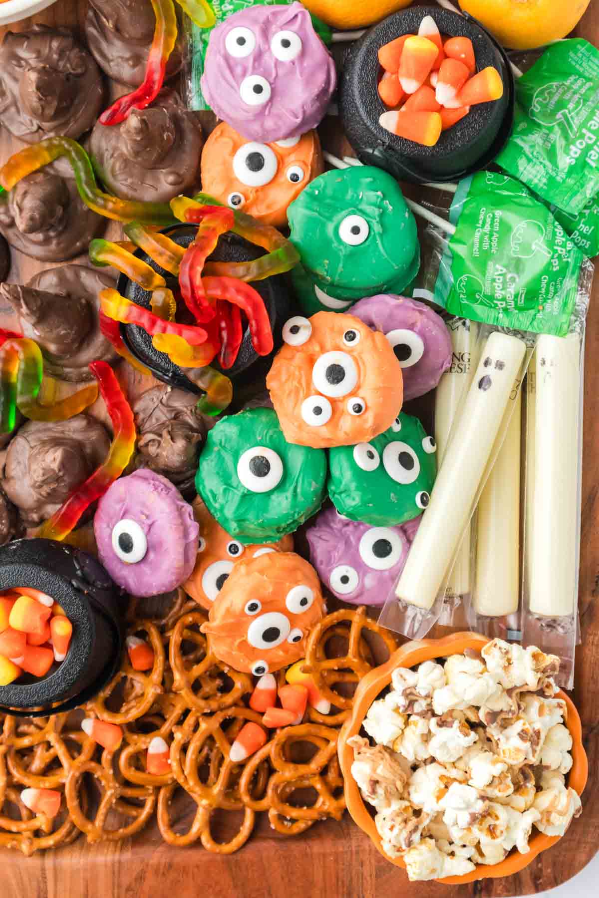 Halloween snack board with monster cookies, pretzels, and string cheese