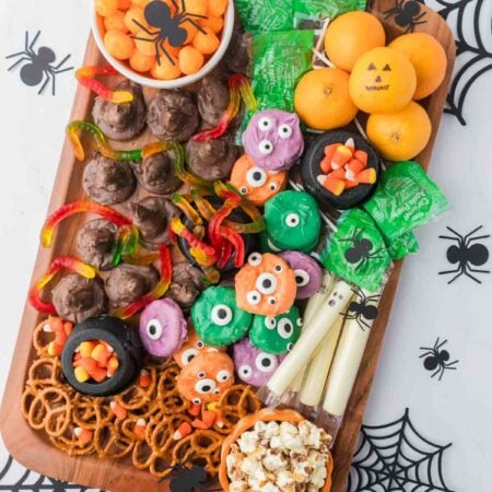 Halloween snack board with cheese puffs, suckers, and ghost string cheese
