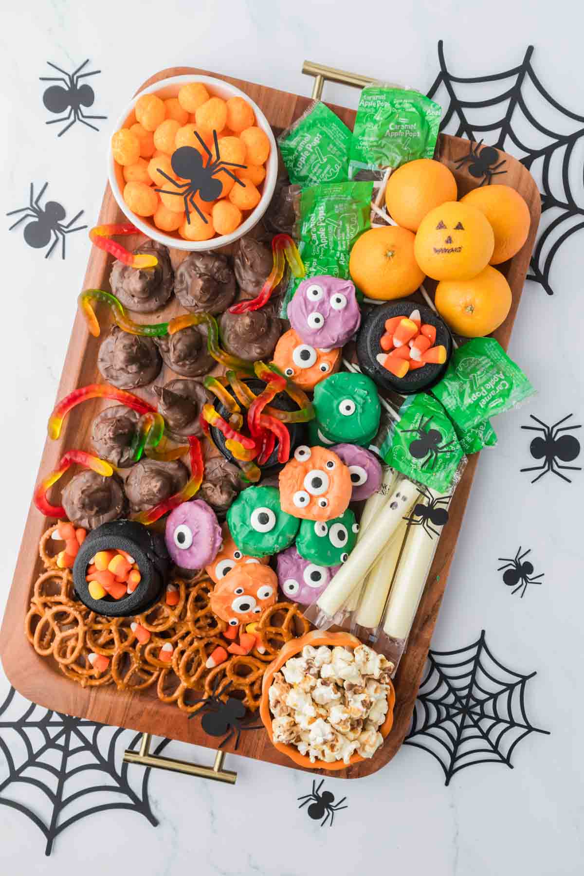 Halloween snack board with cheese puffs, suckers, and ghost string cheese