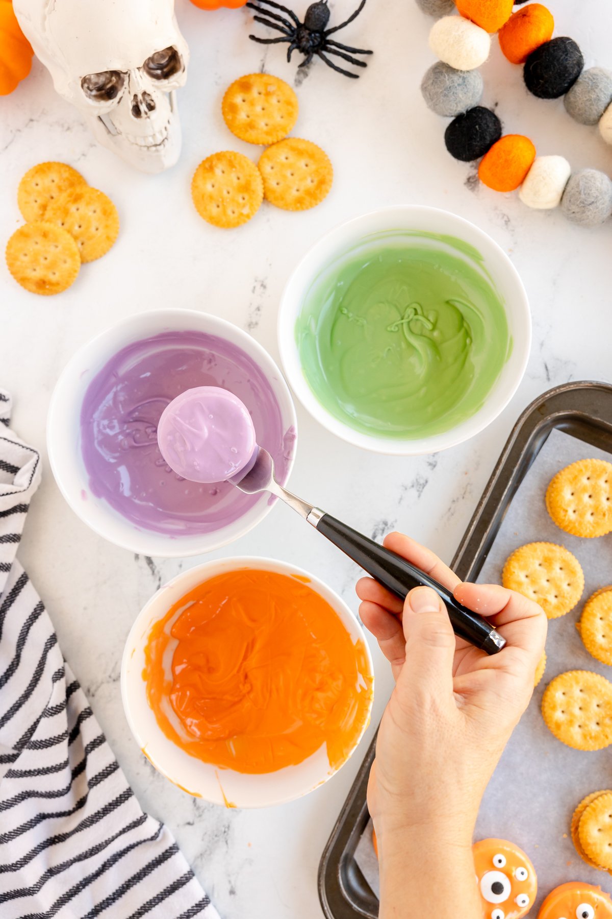 dipping peanut butter crackers in a white bowl of candy melts