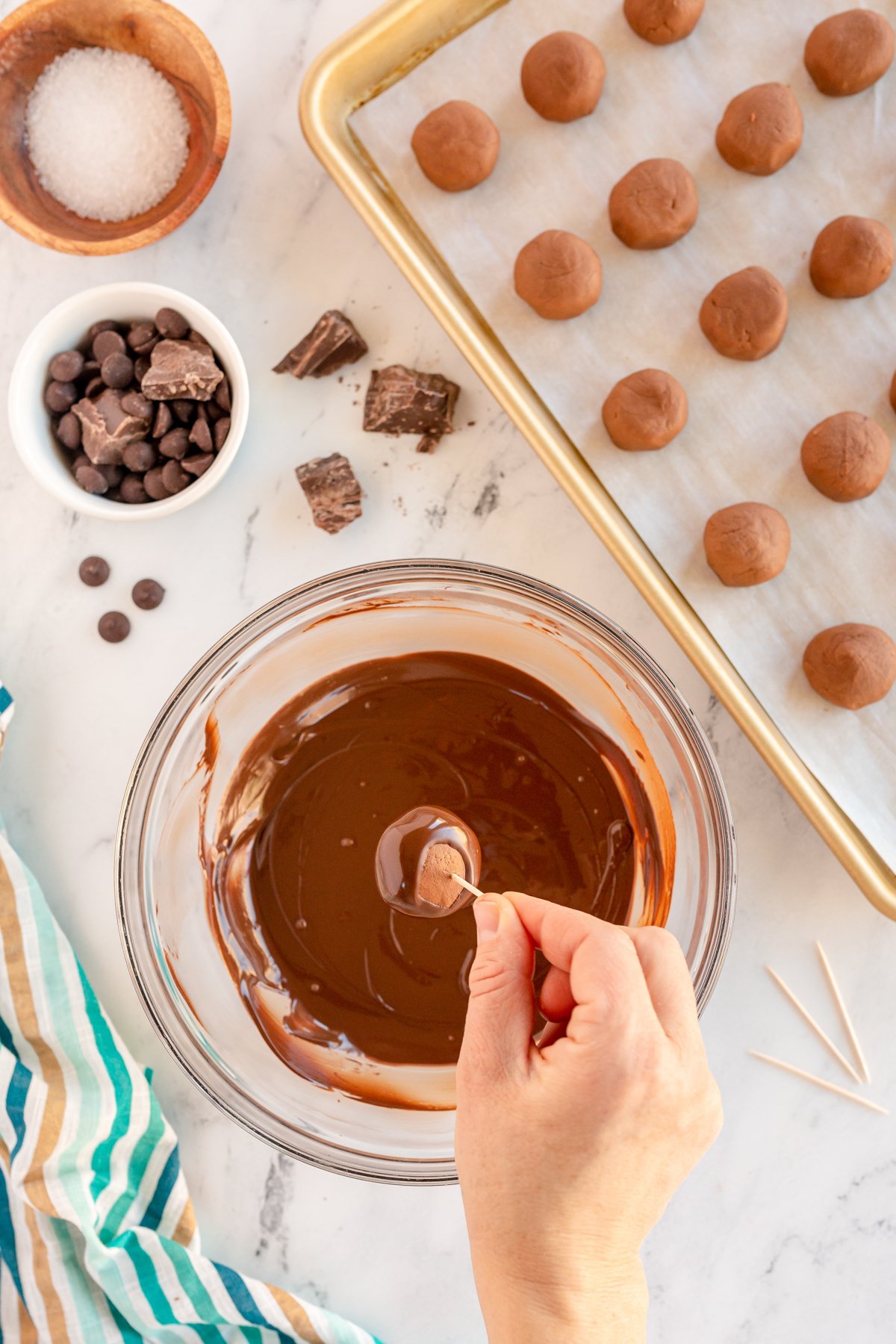 hand dipping buckeye balls into melted chocolate