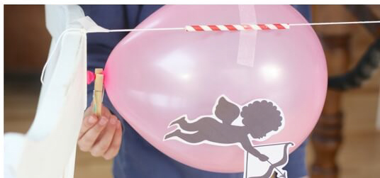 pink balloon with Cupid taped onto it