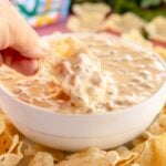 dipping a chip into velveeta sausage dip