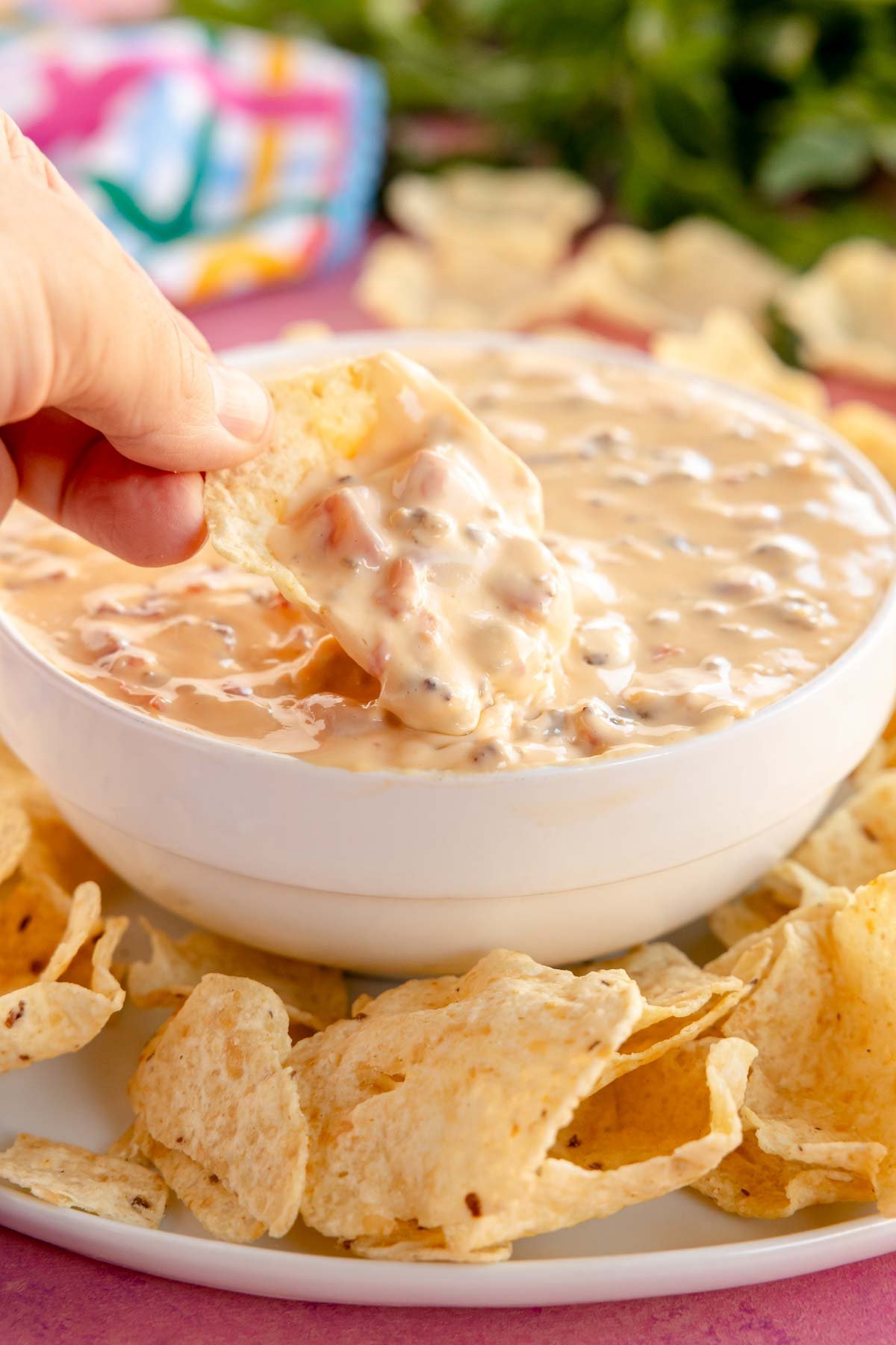 hand dipping a chip into a velveeta sausage cheese dip