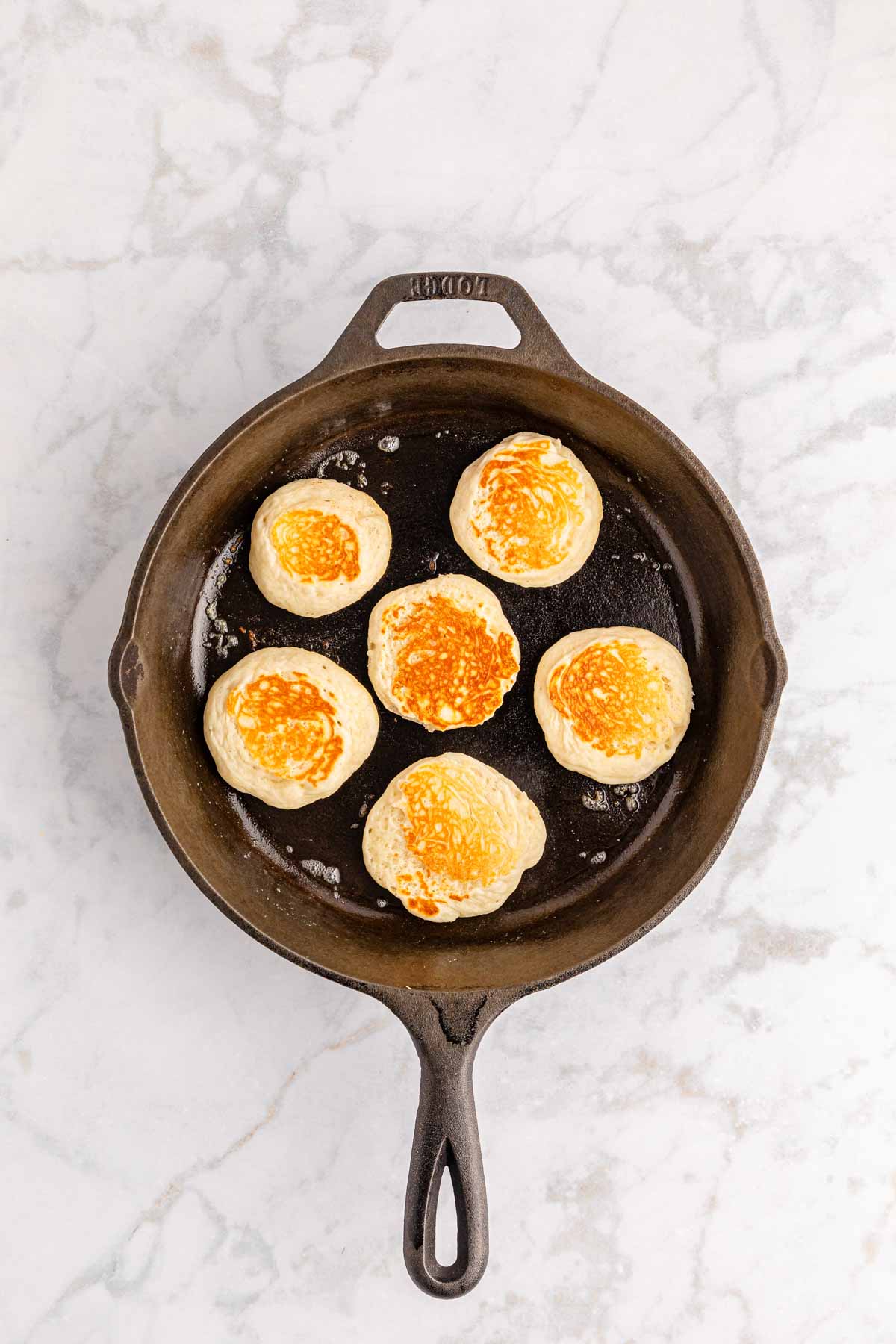 cooking mini pancakes in a cast iron skillet