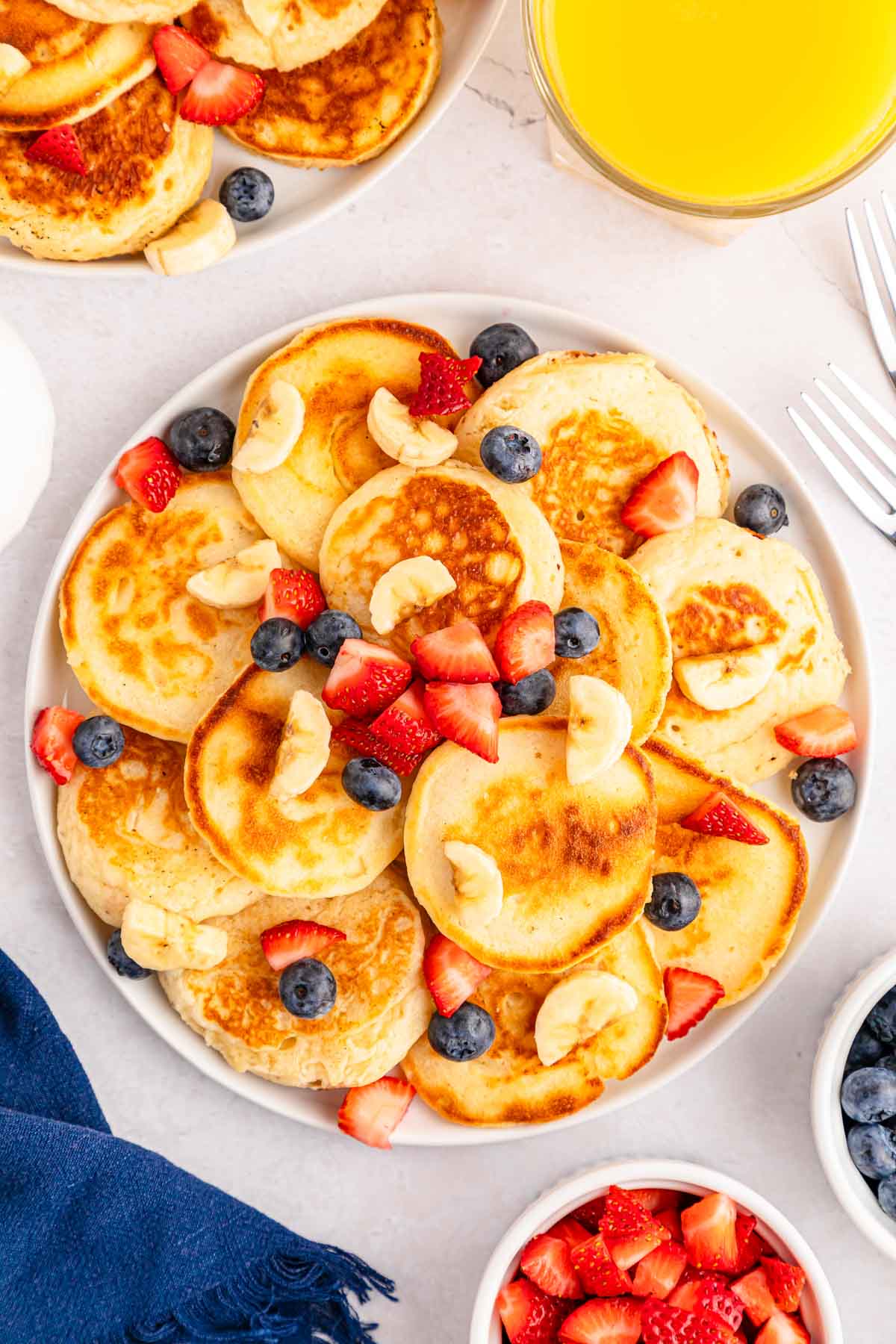 plate full of mini pancakes topped with fruit