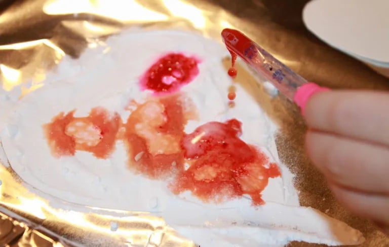 heart shaped coffee filter covered in baking soda with colored vinegar