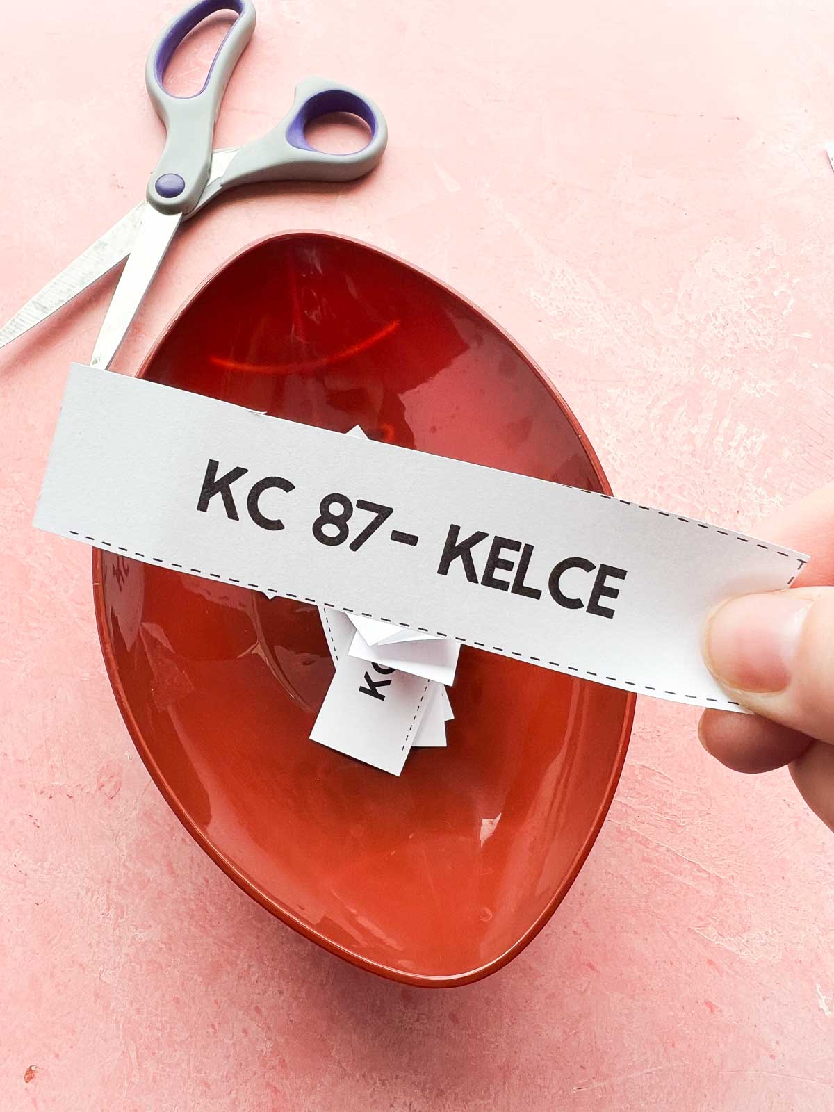 hand holding a piece of paper that says 87 - Kelce