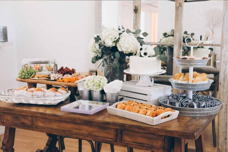 wooden table with a variety of freshly baked pastries an flowers on it