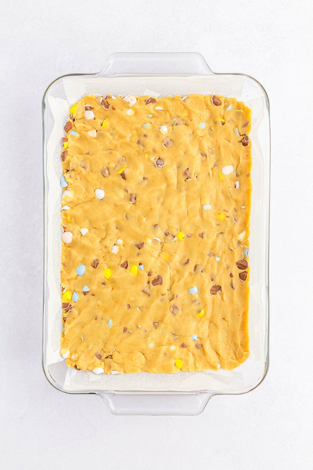 unbaked Cadbury mini egg cookie bar dough in a baking dish