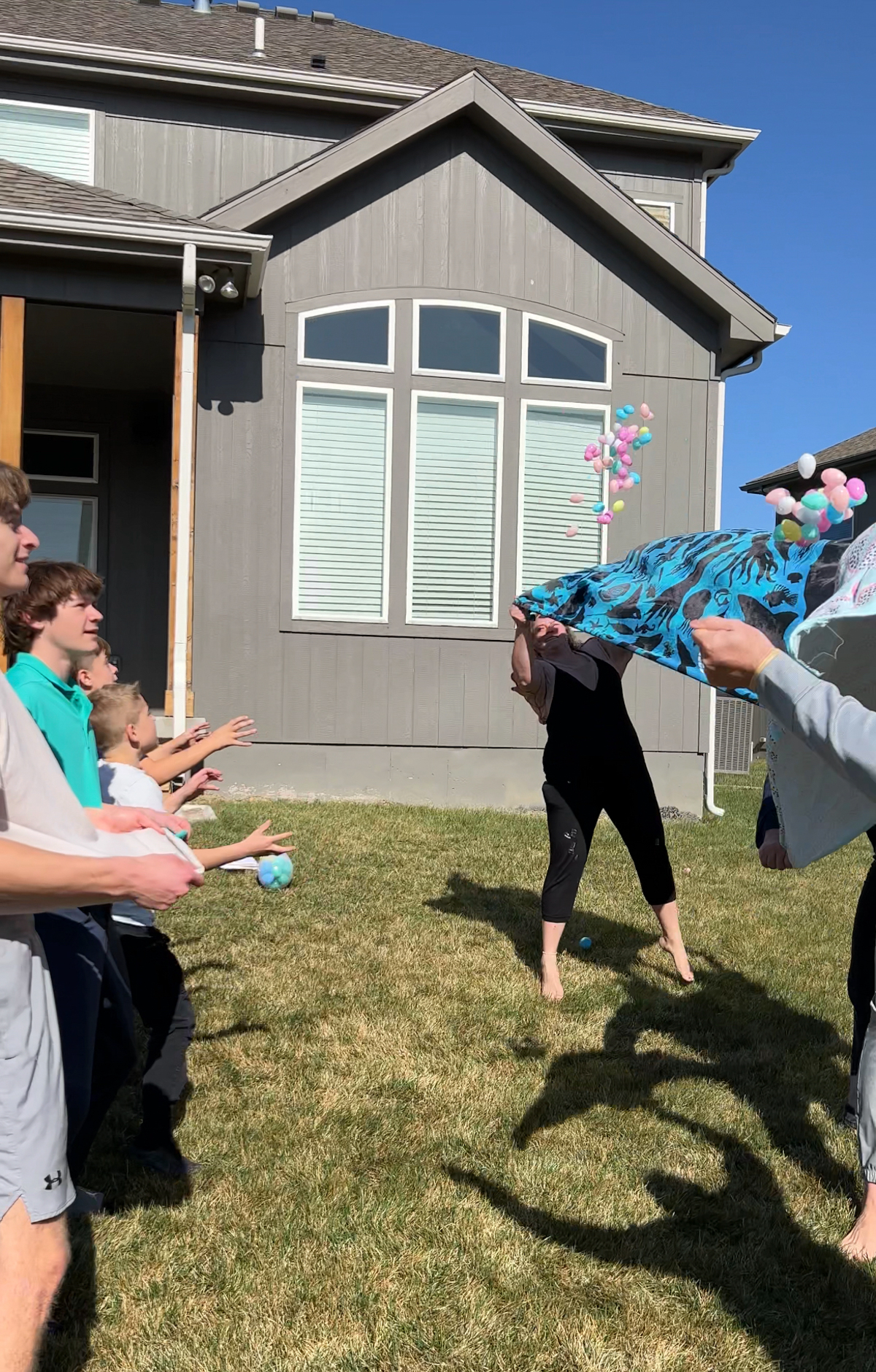 adults tossing eggs using a towel to a bunch of kids