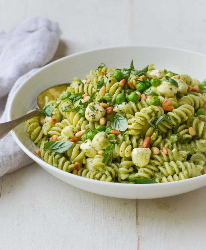 bowl of pea pasta salad garnished with pine nuts