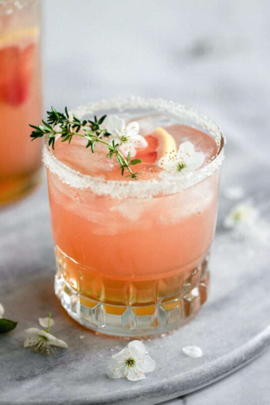 blush colored drink topped with thyme
