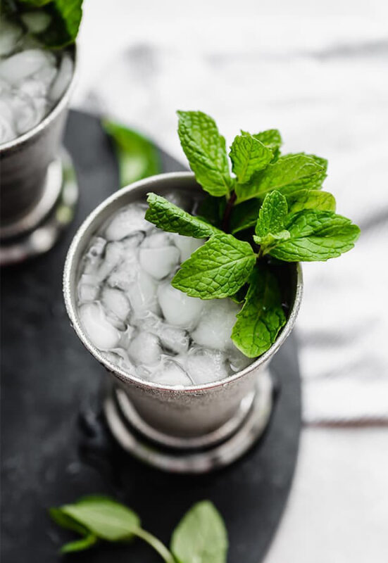drink in a silver cup with ice and mint garnish