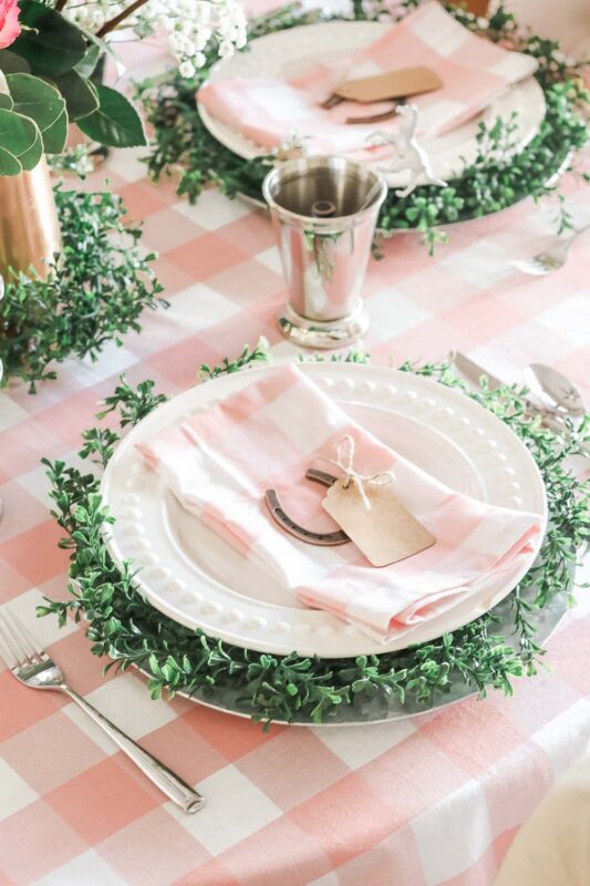 pink gingham place setting with greenery decoration and horse shoe
