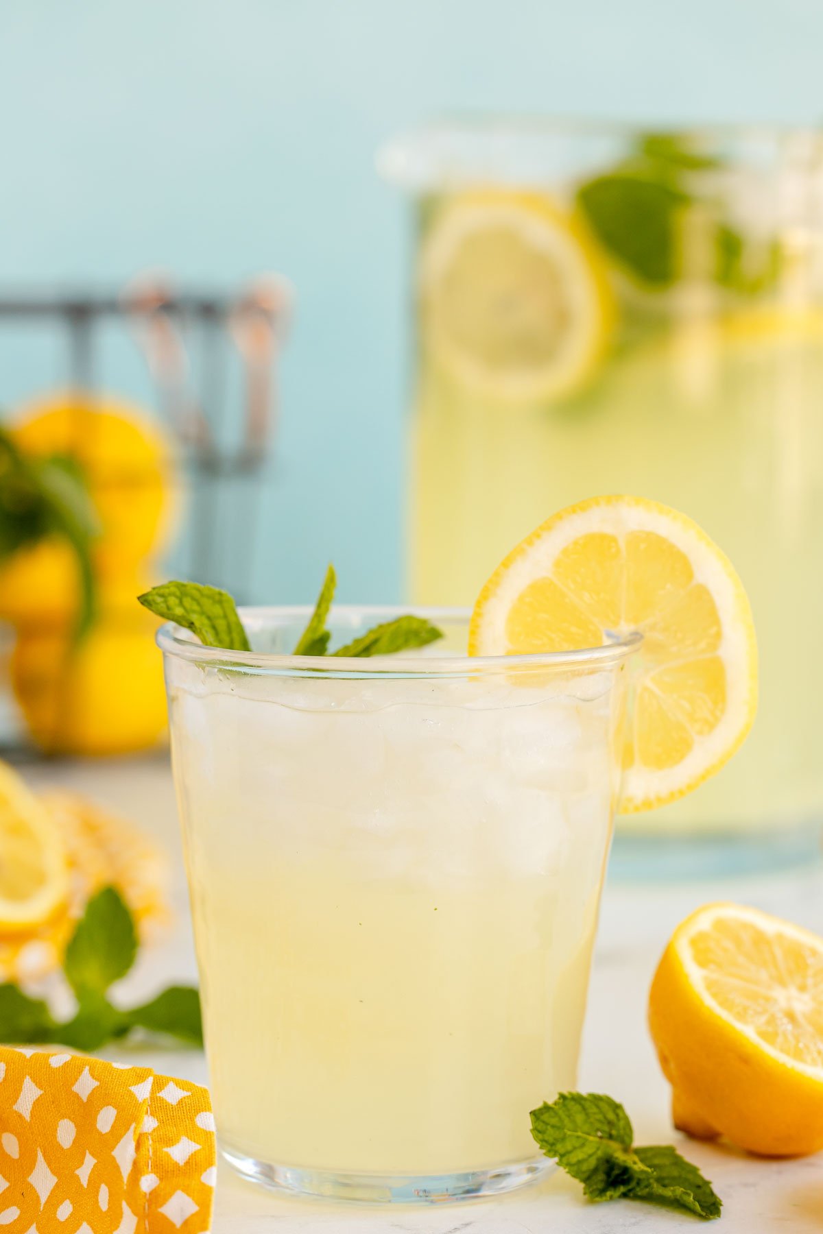 glass of mint lemonade with with a pitcher in the background