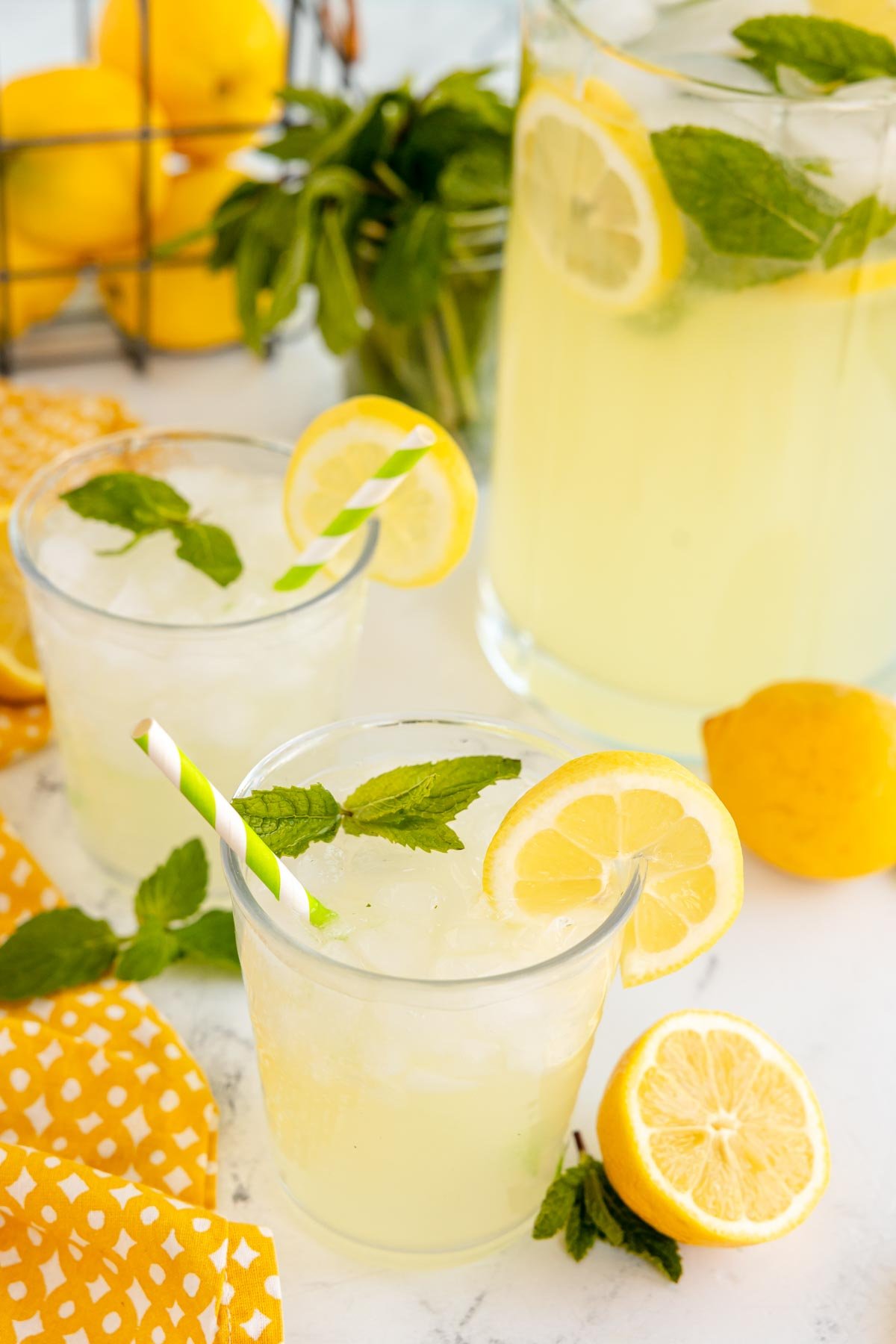 two glasses of mint lemonade with yellow straws