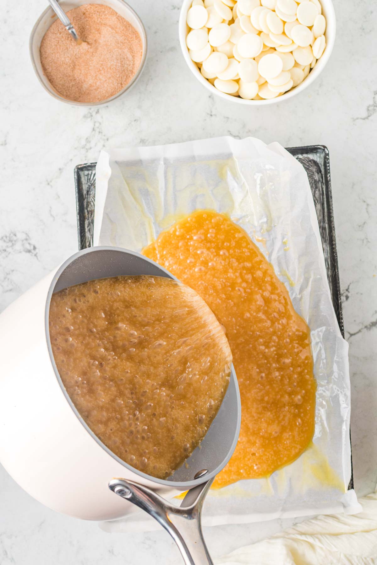 pouring hot toffee onto a sheet pan