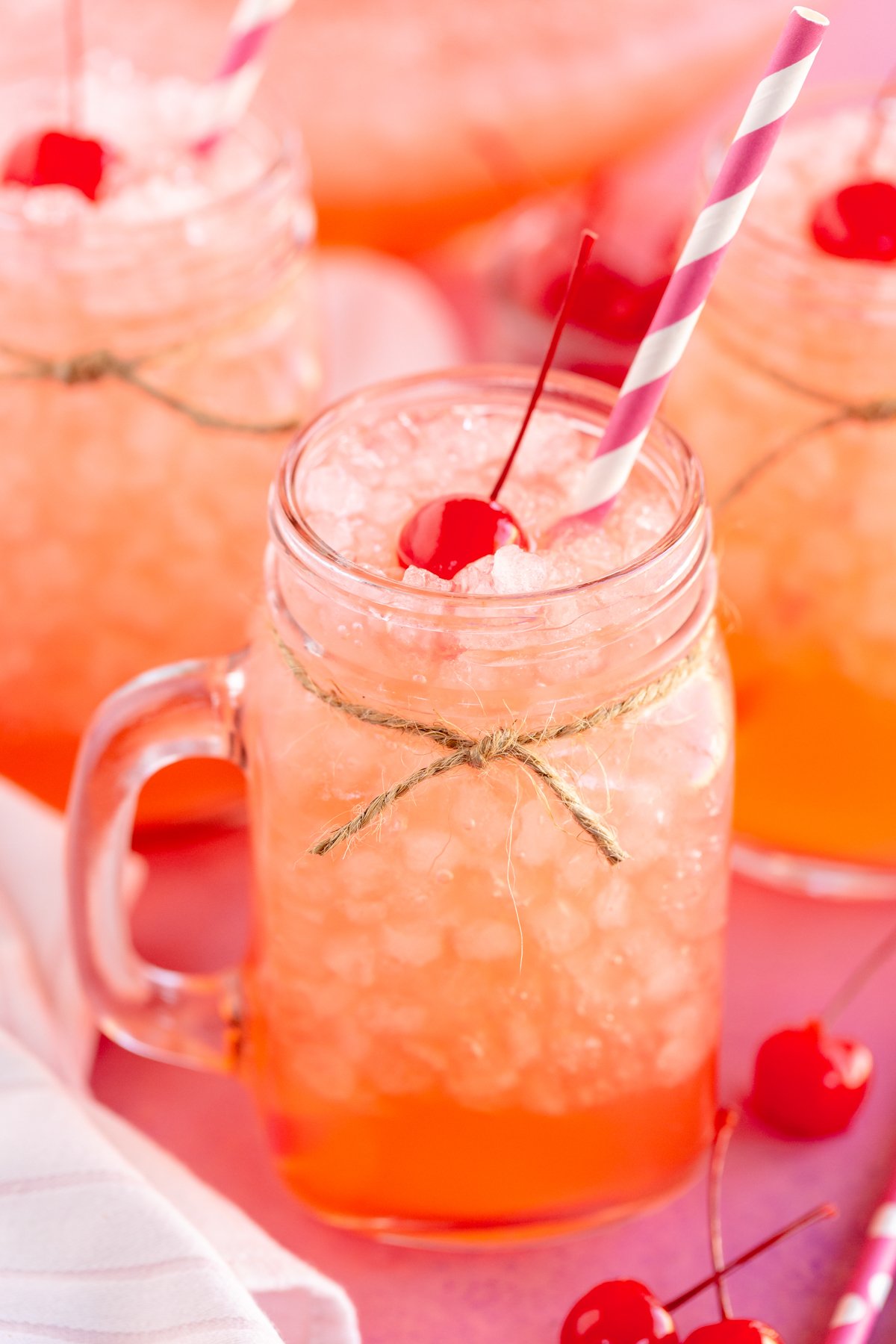 glass with pink punch in it and a straw sticking out