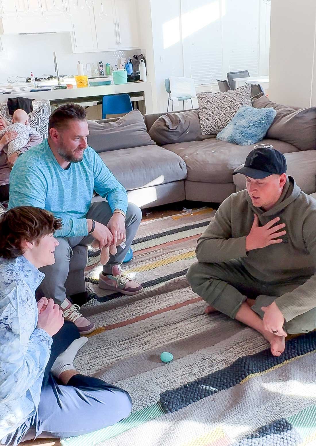 three men sitting in a circle with one egg in between them 