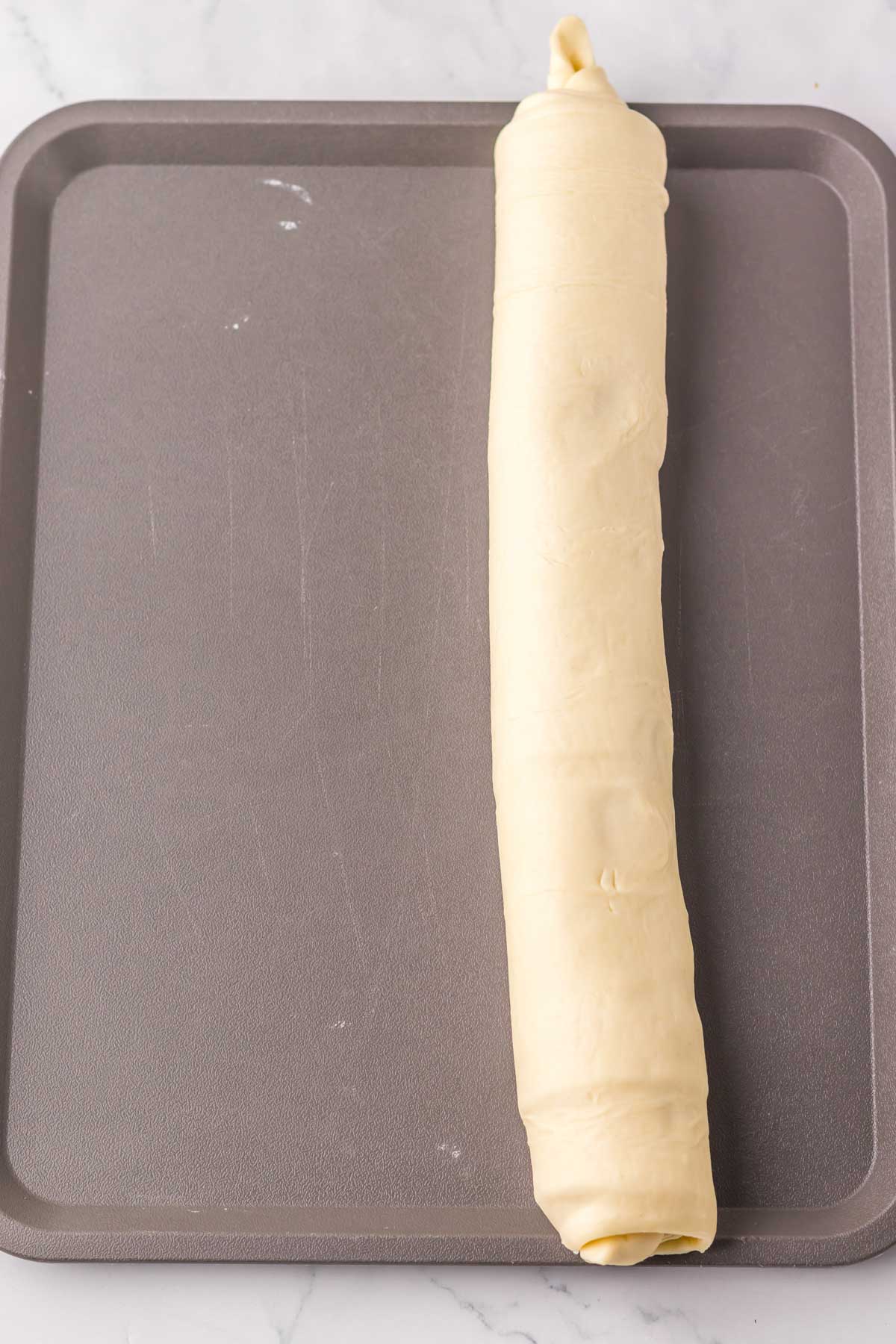 puff pastry ham and cheese roll on a baking sheet