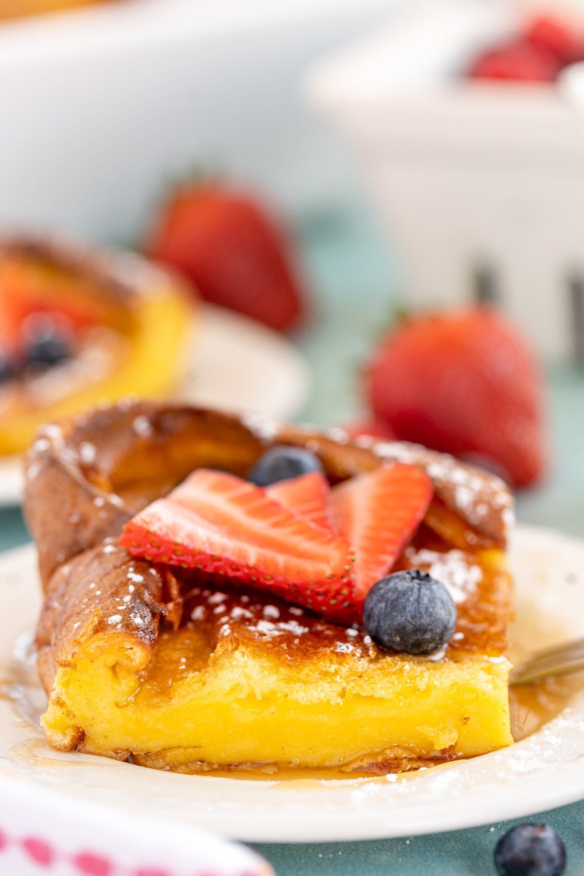 piece of German pancake topped with strawberries and syrup