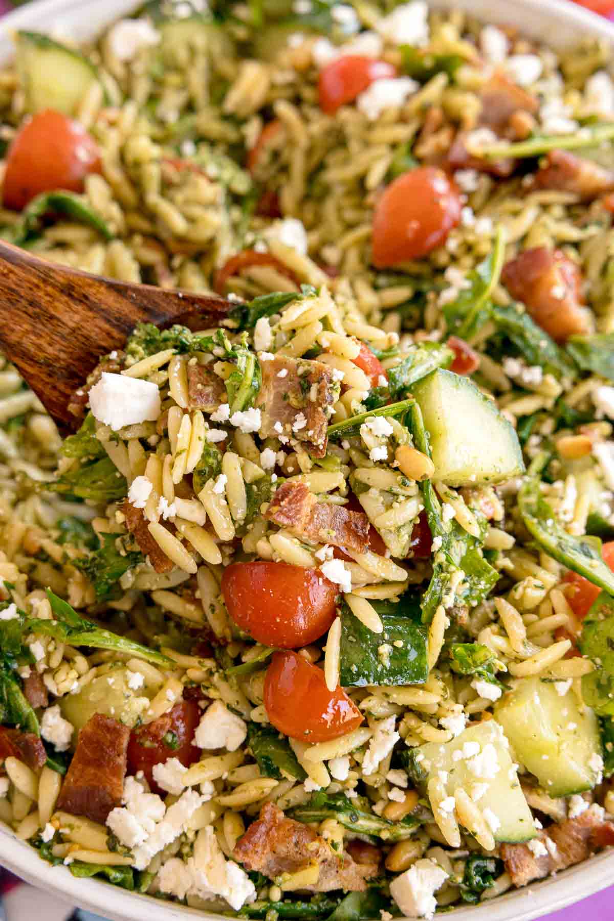 wood spoon in a pesto orzo salad