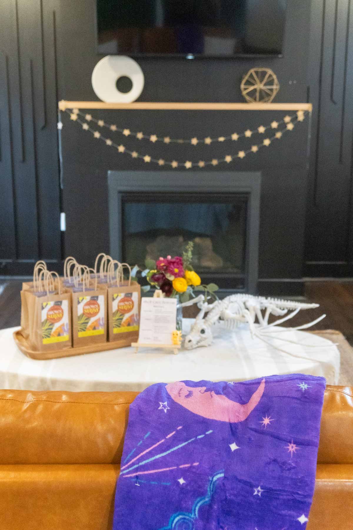 couch with a purple blanket and a book garland in the back