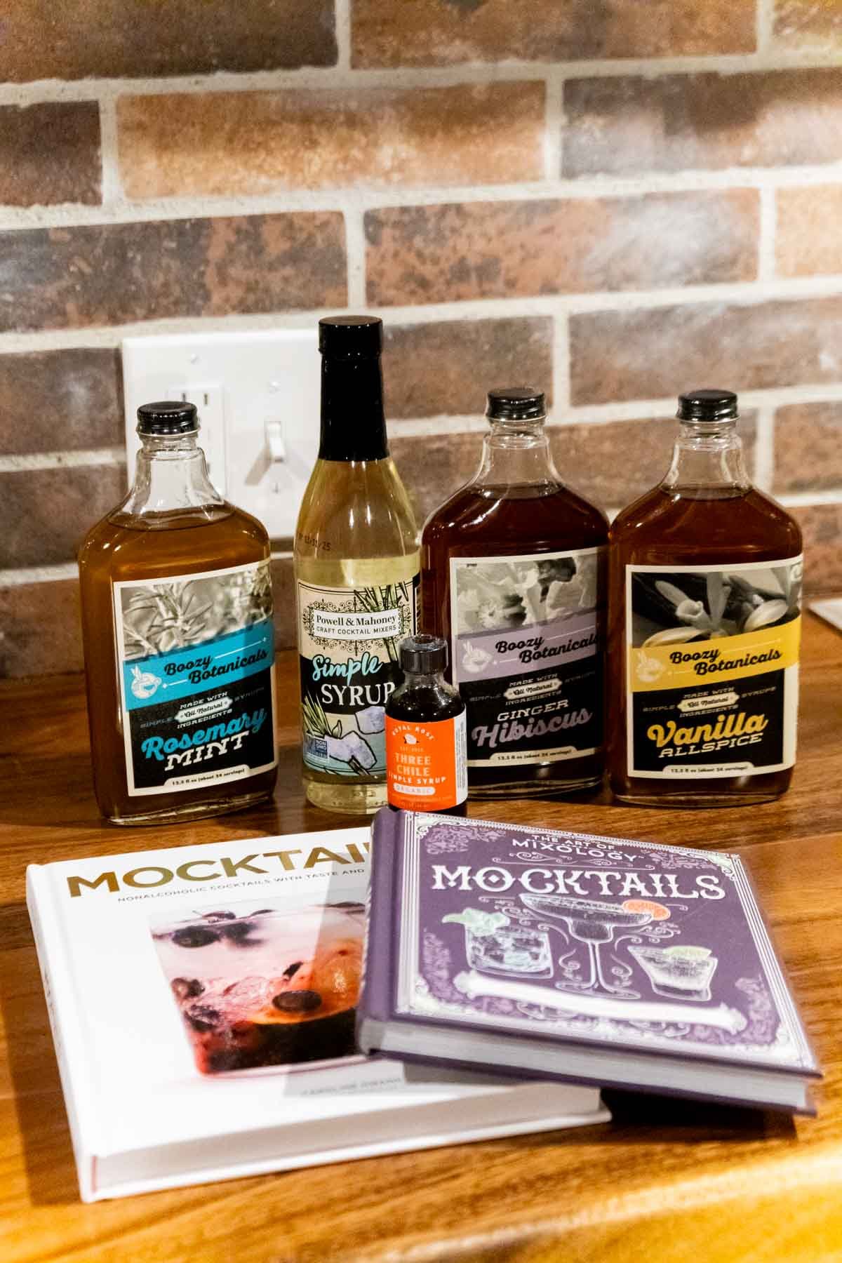 mocktail books and mixers against a brick wall