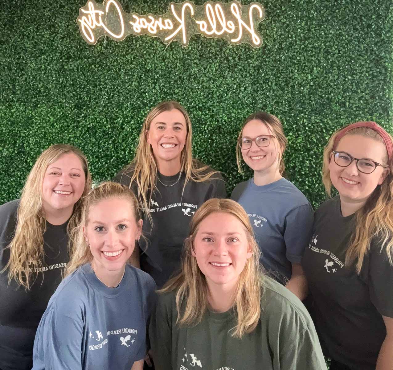 Six women in reading shirts standing in front of a grass wall