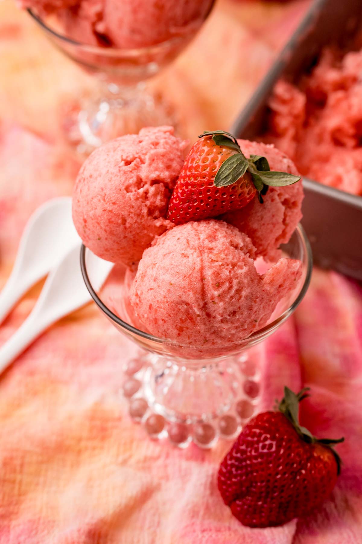 glass with two scoops of strawberry lemon sorbet with a strawberry on top