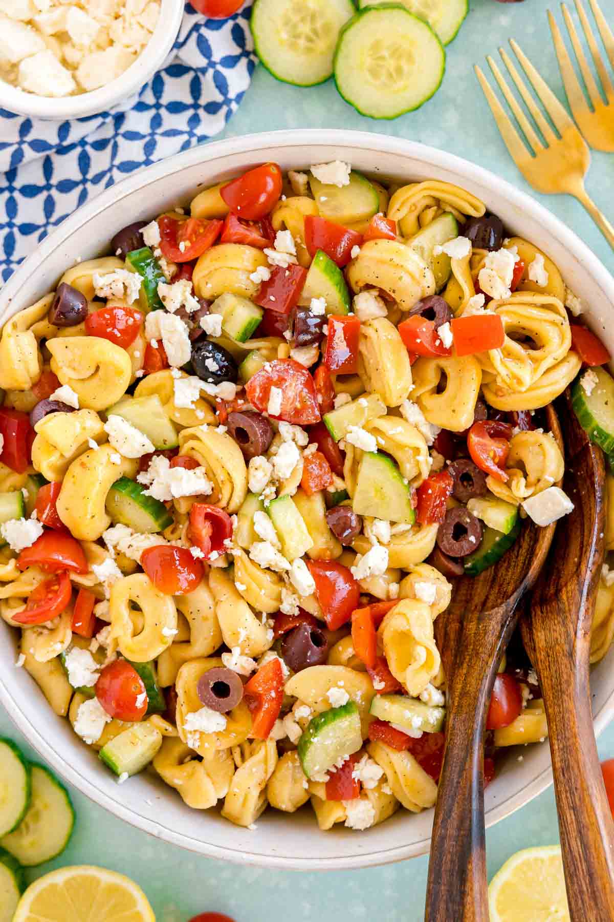 white bowl of tortellini pasta salad with wooden spoons in it