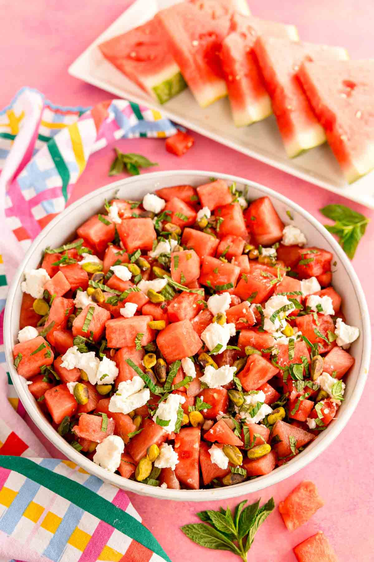 bowl of watermelon mint salad with slices of watermelon in the back
