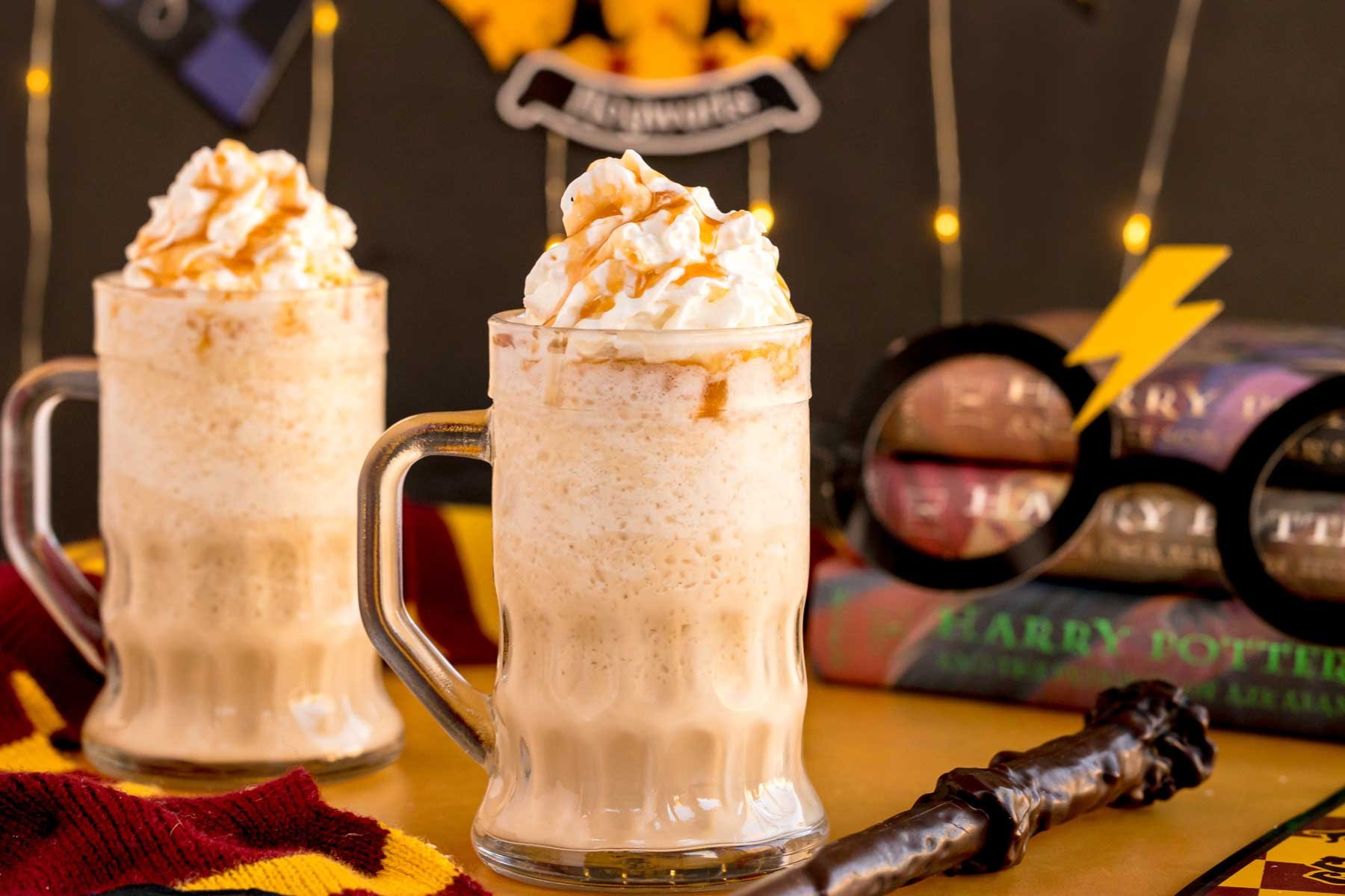 two glasses of frozen buterbeer with a wand next to them