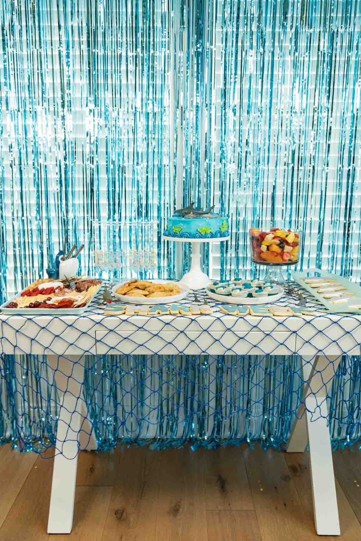 white table decorated with shark party food and a blue fishing net